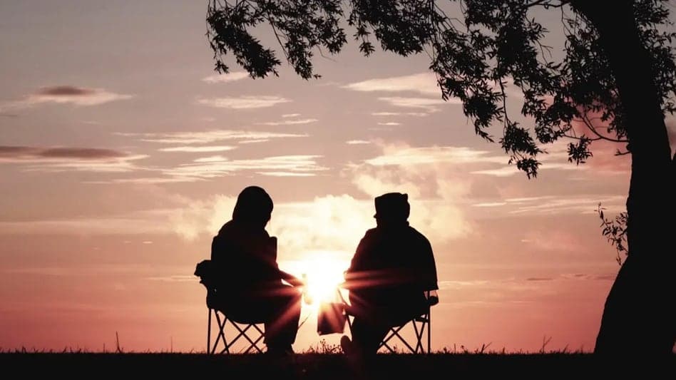 A couple watching the sunset while thinking about retirement account choices.