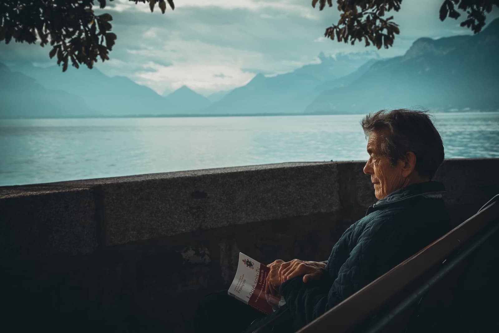 Man sitting by a lake and mountains while thinking about early retirement.