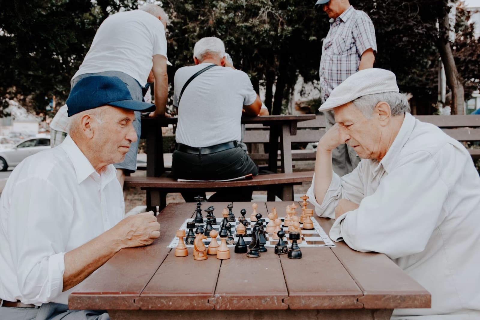 Older men playing chess outdoors while thinking strategically.