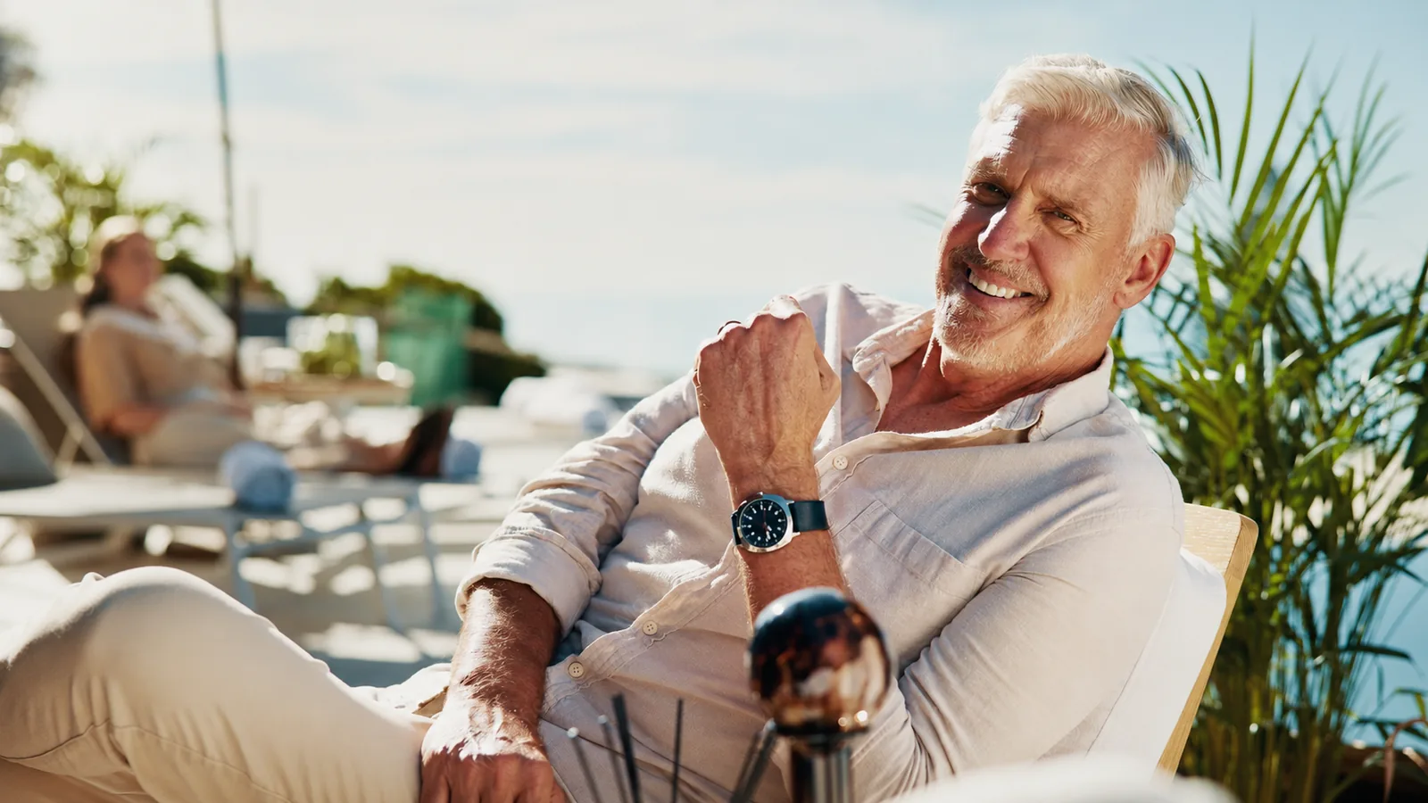 Smiling retiree relaxing outdoors while considering when to claim Social Security.