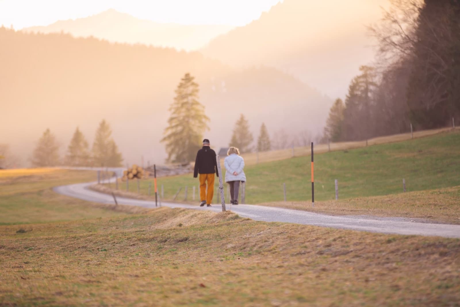Retired couple walking together on a mountain road while planning long-term savings.