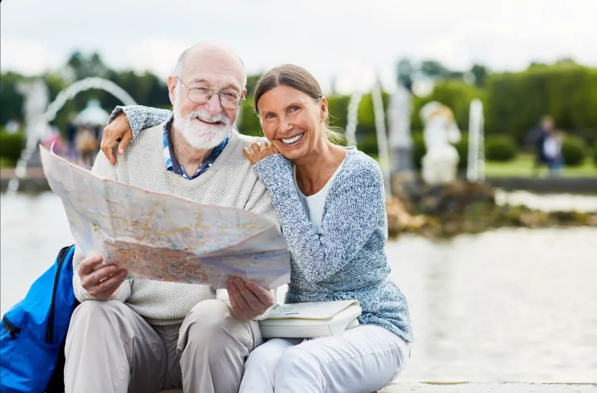 Retired couple planning Social Security claiming age Retired couple reviewing a map while planning Social Security claiming decisions.