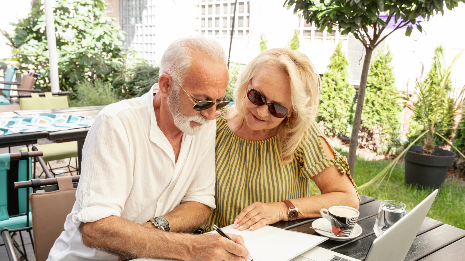 Couple reviewing retirement contribution paperwork and a laptop.